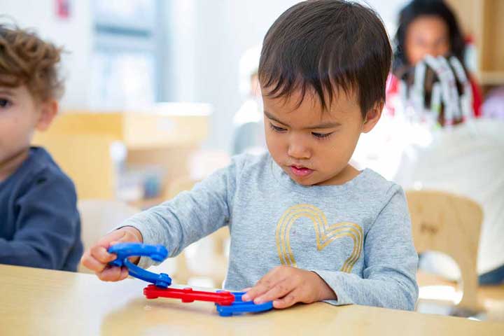 A boy focused on building something with linking blocks.