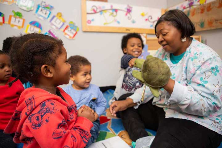 Teacher and children looking at a turtle puppet together.