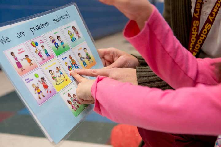 A child pointing at a choice cards on a sheet to solve a problem in the classroom.