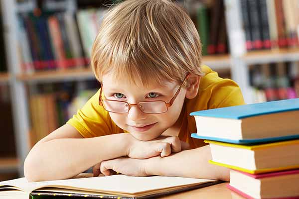 Child with glasses leaning on books